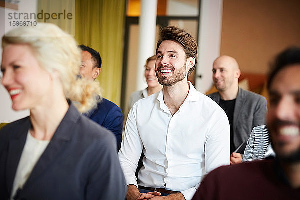 Lächelnde Unternehmer sitzen in Konferenzsitzung am Arbeitsplatz