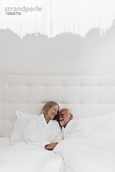 Glückliches romantisches Seniorenpaar im Bett im Hotelzimmer