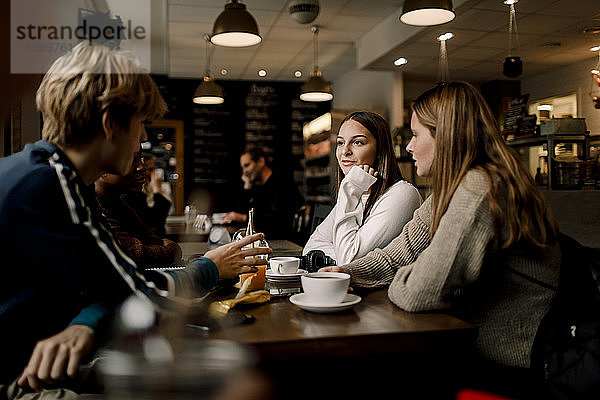 Teenager-Freunde unterhalten sich  während sie im Tischcafé sitzen