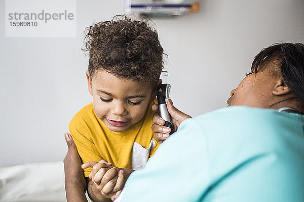 Weibliche Kinderärztin untersucht Ohr des Jungen in medizinischer Klinik