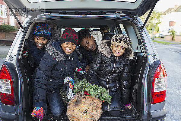 Porträt glückliche Brüder und Schwester mit Weihnachtsbaum auf dem Rücksitz des Autos