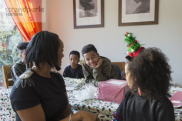Glückliche Familie packt Weihnachtsgeschenke bei Tisch ein