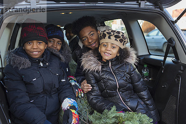 Porträt glückliche Brüder und Schwester mit Weihnachtsbaum auf dem Rücksitz des Autos