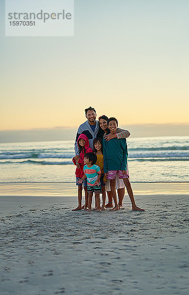 Porträt einer glücklichen  liebevollen Familie am Strand bei Sonnenuntergang