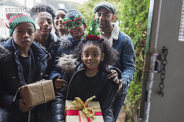 Portrait glückliche Familie beim Überreichen von Weihnachtsgeschenken vor der Haustür