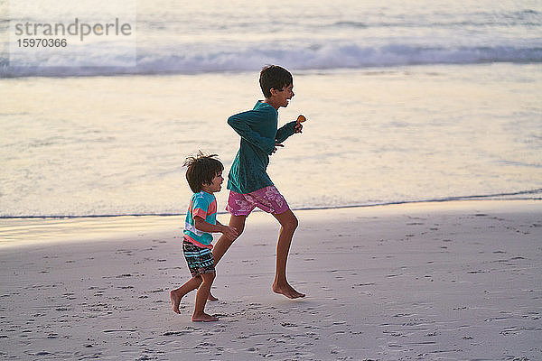 Glückliche Brüder laufen am Strand des Ozeans