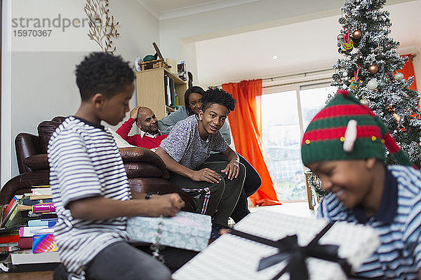 Familie öffnet Weihnachtsgeschenke im Wohnzimmer