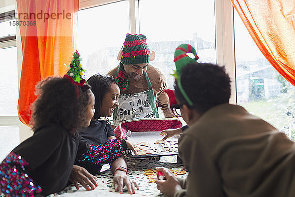 Glückliche Familie schmückt Weihnachtsplätzchen bei Tisch