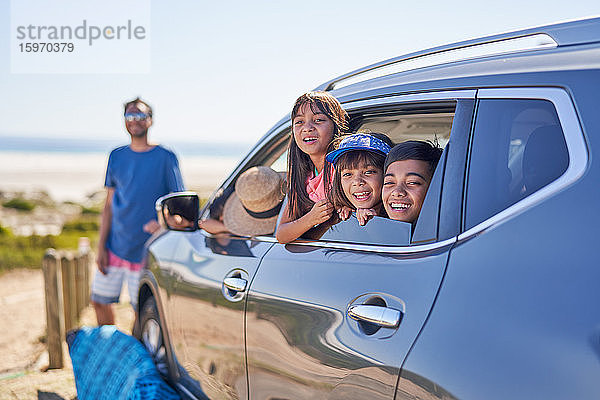 Porträt einer glücklichen Familie im Auto am sonnigen Strand