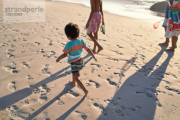 Süßer Junge läuft mit Familie am Strand