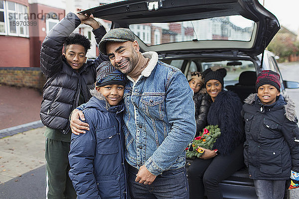 Porträt einer glücklichen Familie  die sich auf dem Rücksitz eines Autos umarmt