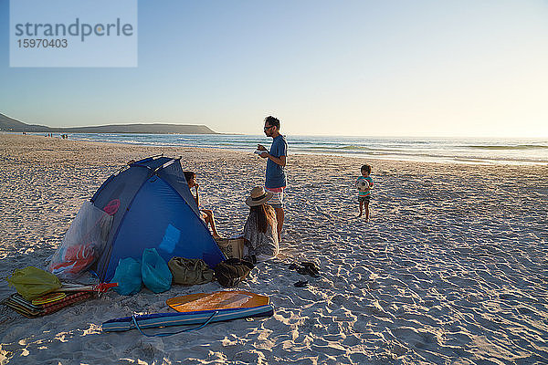 Familie entspannt und spielt im Zelt am Strand des Ozeans  Kapstadt