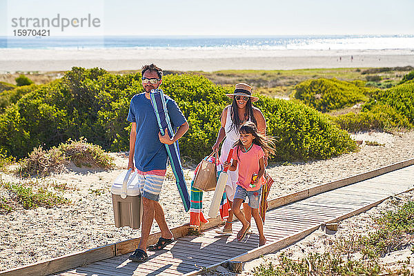 Glückliche Familie beim Spaziergang an der sonnigen Strandpromenade