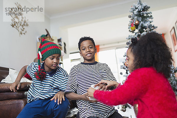 Brüder und Schwestern öffnen Weihnachtsgeschenke im Wohnzimmer