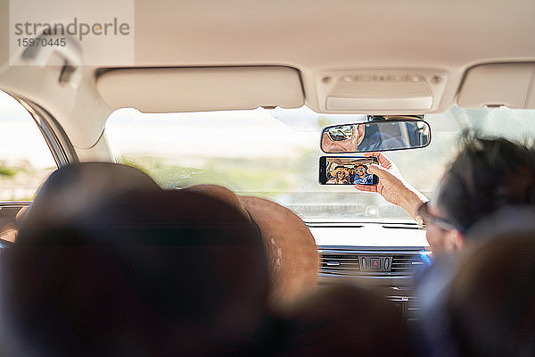 Familie nimmt Selfie mit Fotohandy im Auto mit