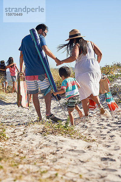 Familienspaziergang im Sand am sonnigen Strand