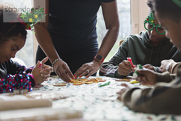 Familie schmückt Weihnachtsplätzchen bei Tisch