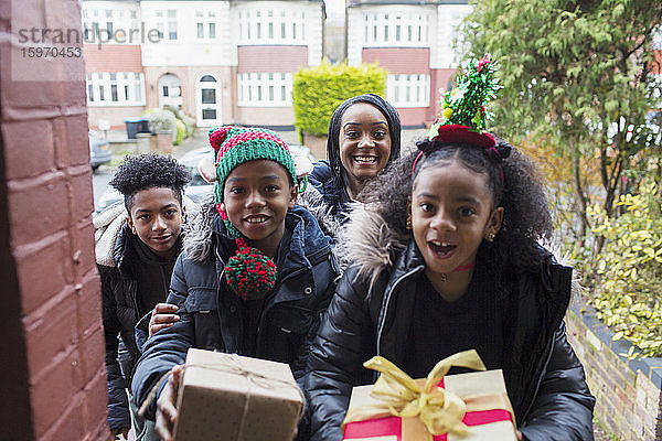 Porträt einer glücklichen Familie beim Überreichen von Weihnachtsgeschenken auf der Vordertreppe