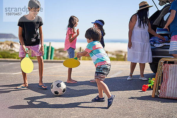 Familie spielt mit Fussball auf Strandparkplatz