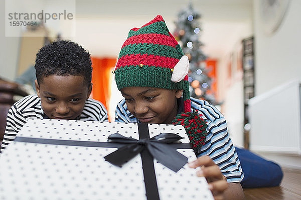 Neugierige Brüder schauen auf Weihnachtsgeschenk