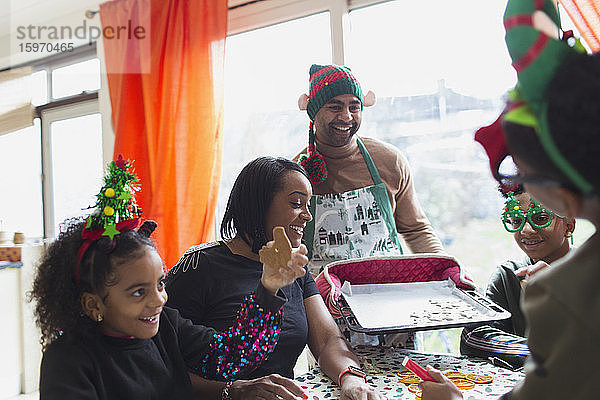 Fröhliche Familie backt und isst Weihnachtsplätzchen bei Tisch