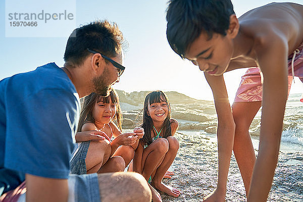 Glückliche Familie spielt am sonnigen Strand