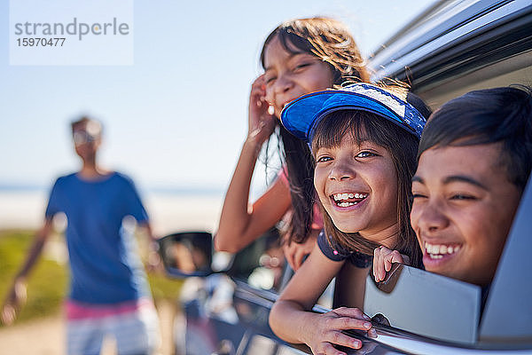 Porträt glücklicher Kinder  die sich aus dem sonnigen Autofenster lehnen
