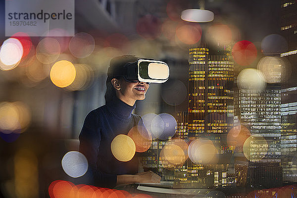 Geschäftsfrau mit Virtual-Reality-Brille im Hochhausbüro bei Nacht