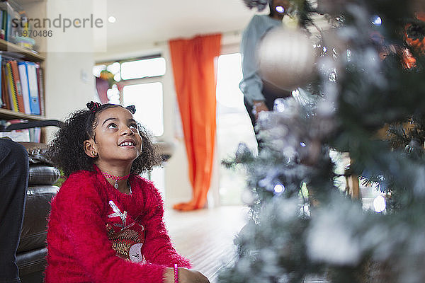 Neugieriges Mädchen schaut zum Weihnachtsbaum hinauf
