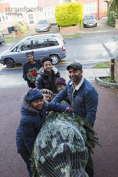 Porträt glückliche Familie mit Weihnachtsbaum in der Einfahrt