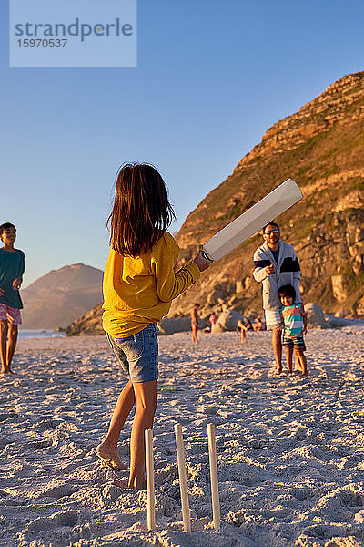 Familie spielt Kricket am Sommerstrand