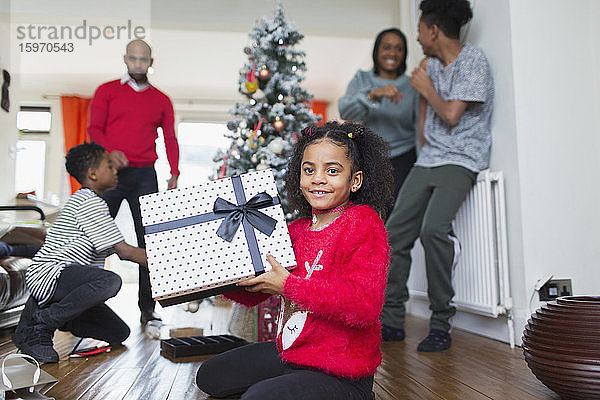 Porträt eines glücklichen Mädchens mit Weihnachtsgeschenk im Wohnzimmer