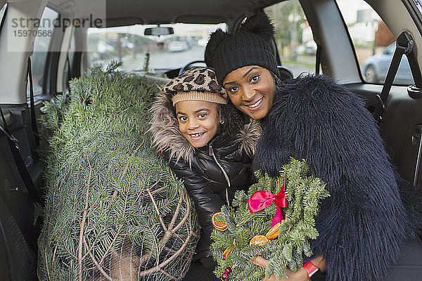 Porträt glückliche Mutter und Tochter mit Weihnachtsbaum im Auto