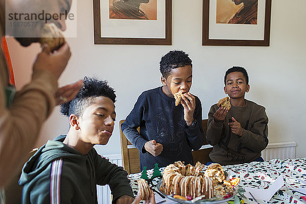 Vater und Söhne essen Weihnachtskuchen bei Tisch