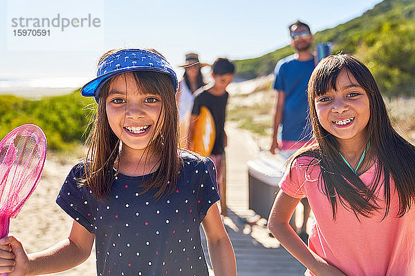 Porträt glücklicher Schwestern am sonnigen Strand mit Familie