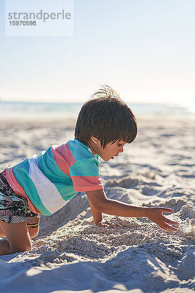 Junge spielt im Sand am sonnigen Sommerstrand