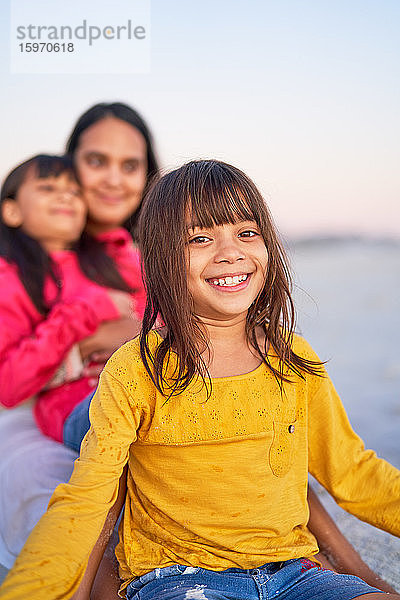 Porträt eines glücklichen Mädchens  das sich mit der Familie am Strand entspannt
