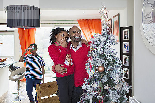 Vater und Tochter schauen auf den Weihnachtsbaum