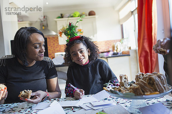 Portrait Mutter und Tochter beim Schreiben von Weihnachtskarten bei Tisch