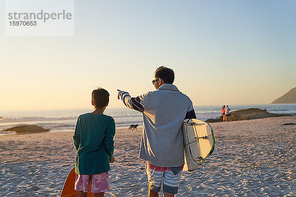 Vater und Sohn mit Surfbrettern am sonnigen Strand