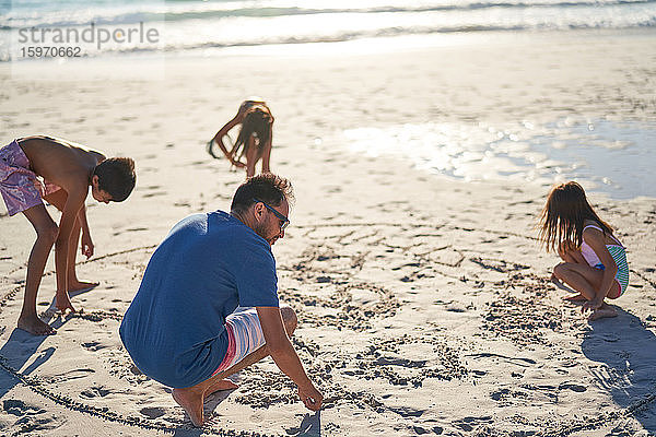 Familienzeichnung im Sand am sonnigen Strand