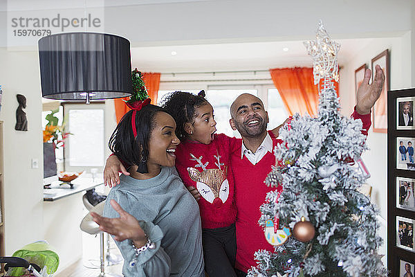 Glückliche Familie schmückt den Weihnachtsbaum im Wohnzimmer