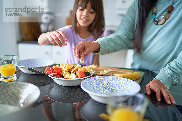 Mutter und Tochter essen Obst in der Küche