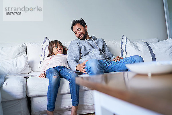 Vater und Tochter entspannen sich auf dem Wohnzimmersofa