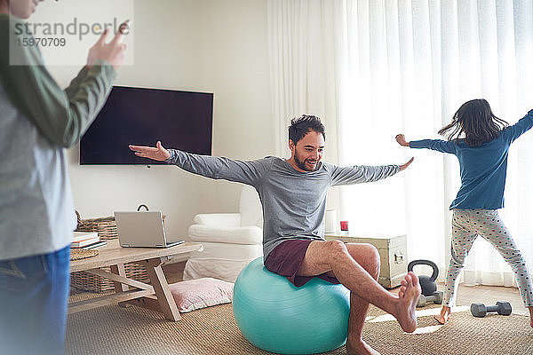 Vater und Kinder üben und spielen im Wohnzimmer