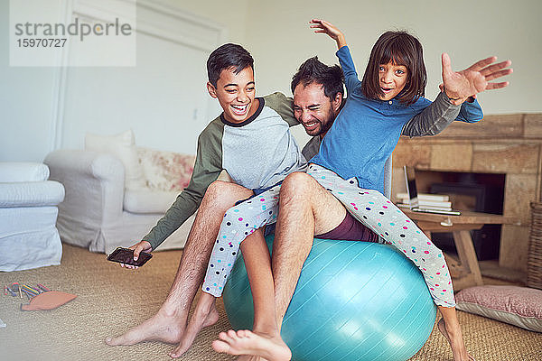 Porträt einer glücklichen Familie beim Spielen auf dem Fitnessball im Wohnzimmer