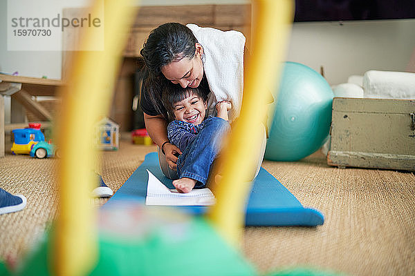 Glückliche Mutter und Sohn spielen auf der Yogamatte