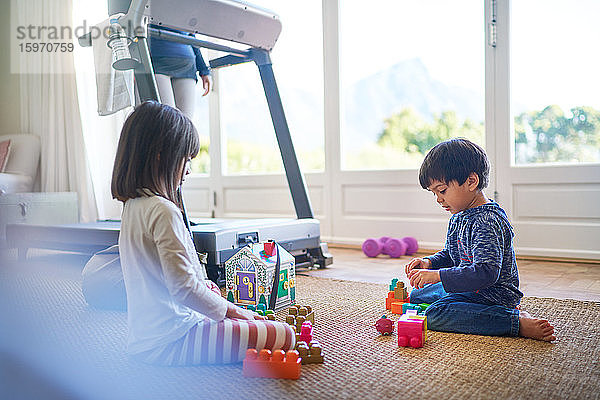 Kinder spielen mit Spielzeug auf dem Boden von der Mutter auf dem Laufband