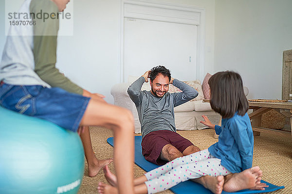 Vater und Kinder trainieren im Wohnzimmer