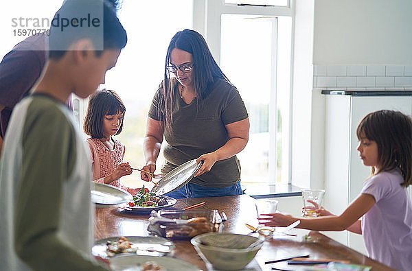 Familie räumt Essen und Geschirr vom Mittagstisch